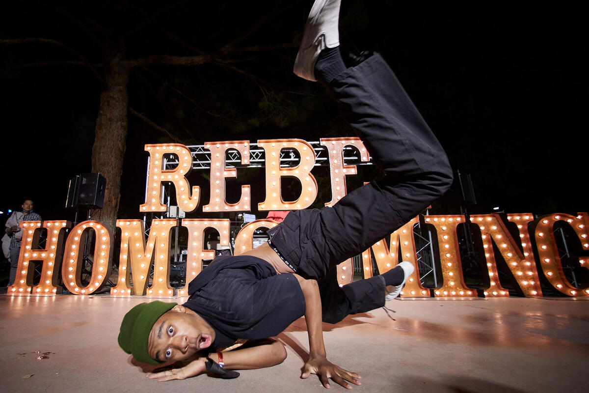 A man break dancing in front of &quot;Rebel Homecoming&quot; sign